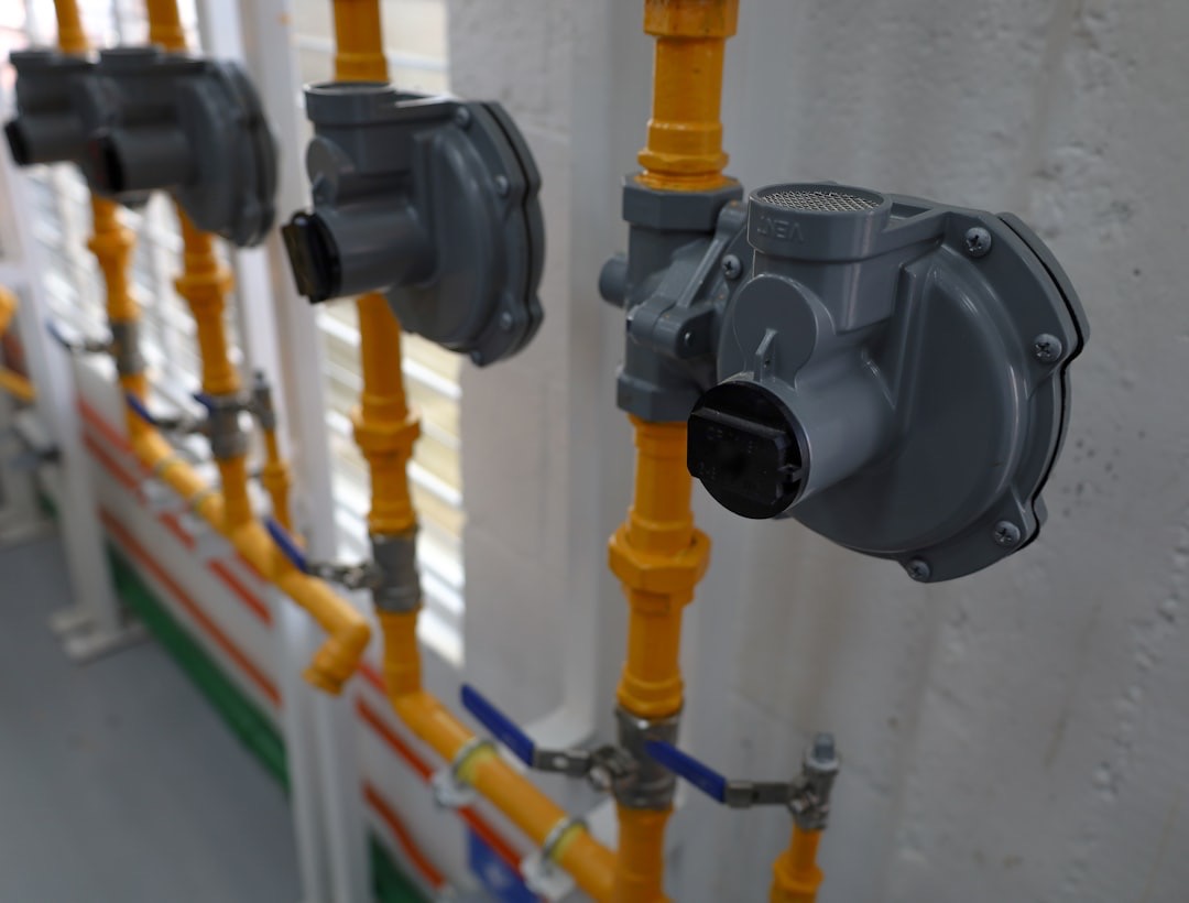 Gray gas pressure regulators connected to yellow pipes and blue valves.
